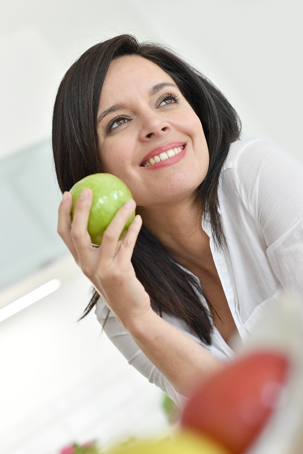 Beautiful mature woman eating green apple